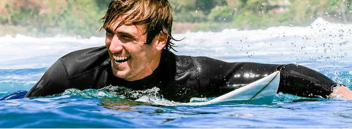 Surfer enjoying a warm summer day in Scheveningen wearing a comfortable neoprene top from our collection. Noordzee Boardstore surfshop Surfschool webshop surfboardrepairs Scheveningen