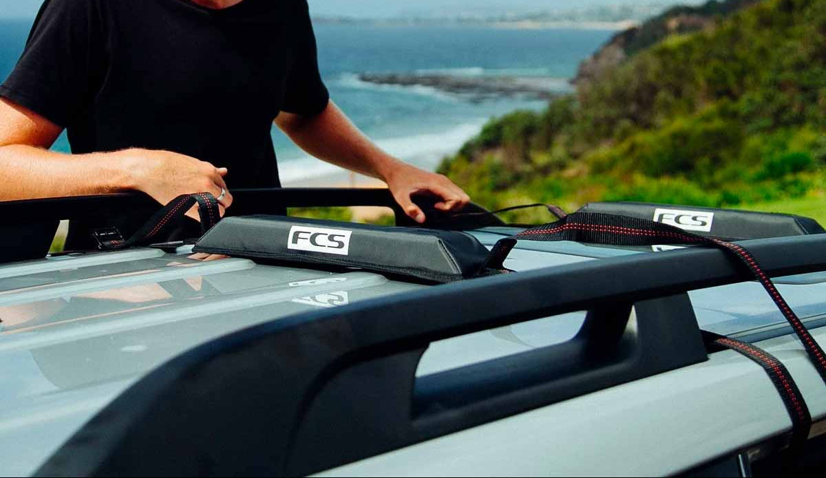 Surfer easily strapping their board to the roof of their car with soft racks from Noordzee Boardstore. Noordzee Boardstore surfshop Surfschool webshop surfboardrepairs Scheveningen