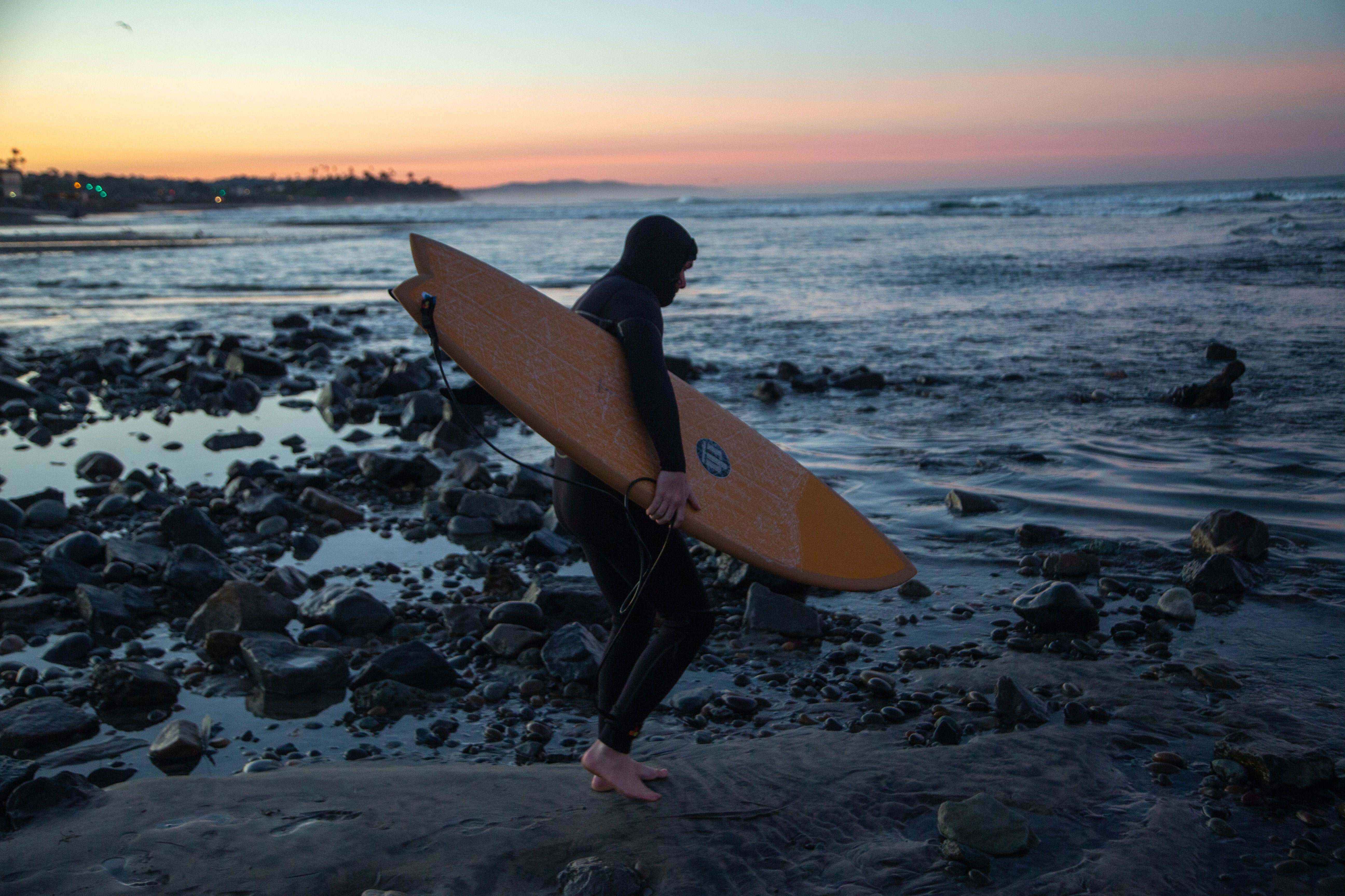 Surfer holding a block of surfboard wax, an essential accessory from Noordzee Boardstore. Noordzee Boardstore surfshop Surfschool webshop surfboardrepairs Scheveningen