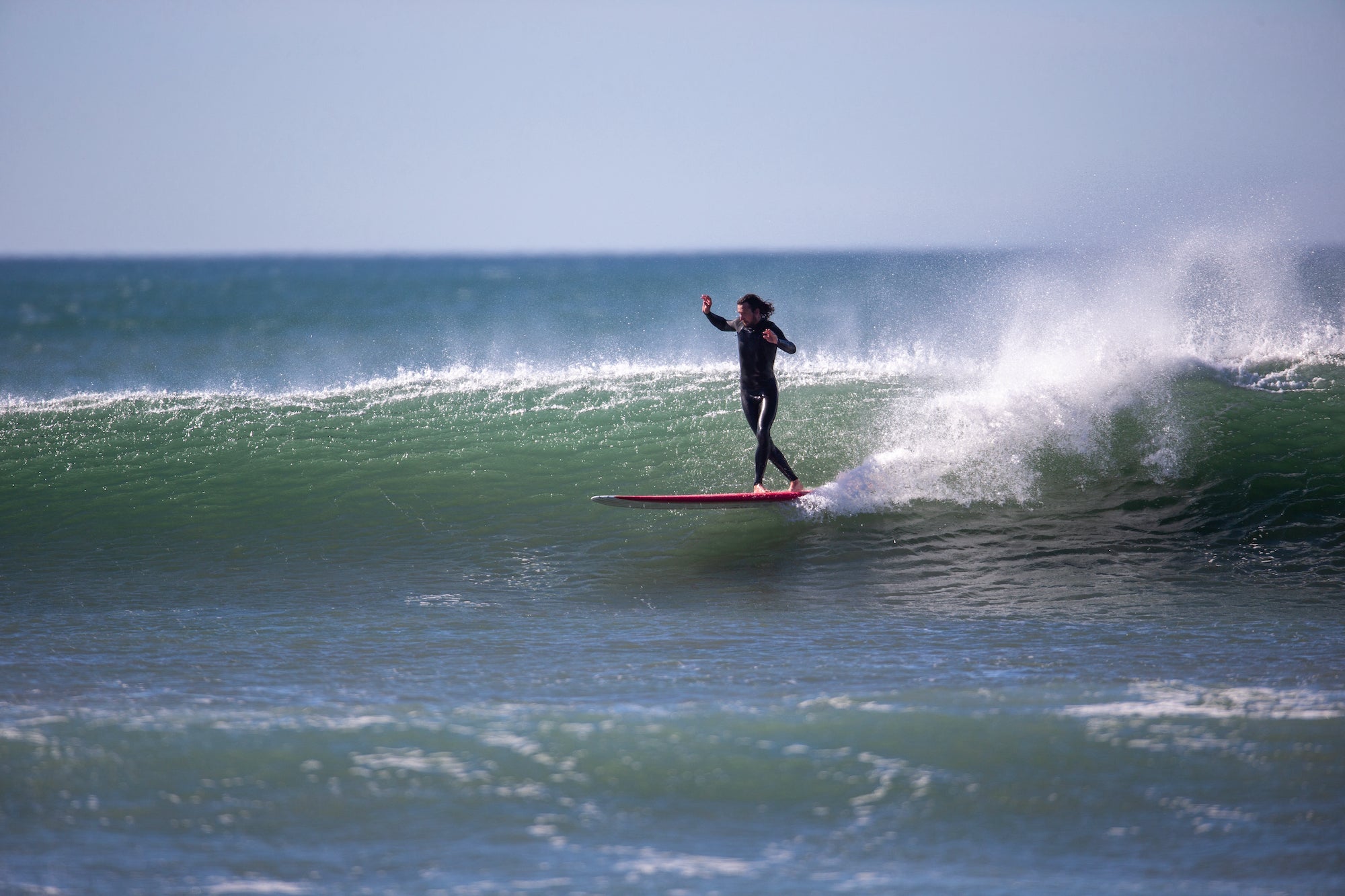 Surfer enjoying the glide on a classic longboard from our expert collection in The Hague. Noordzee Boardstore surfshop Surfschool webshop surfboardrepairs Scheveningen