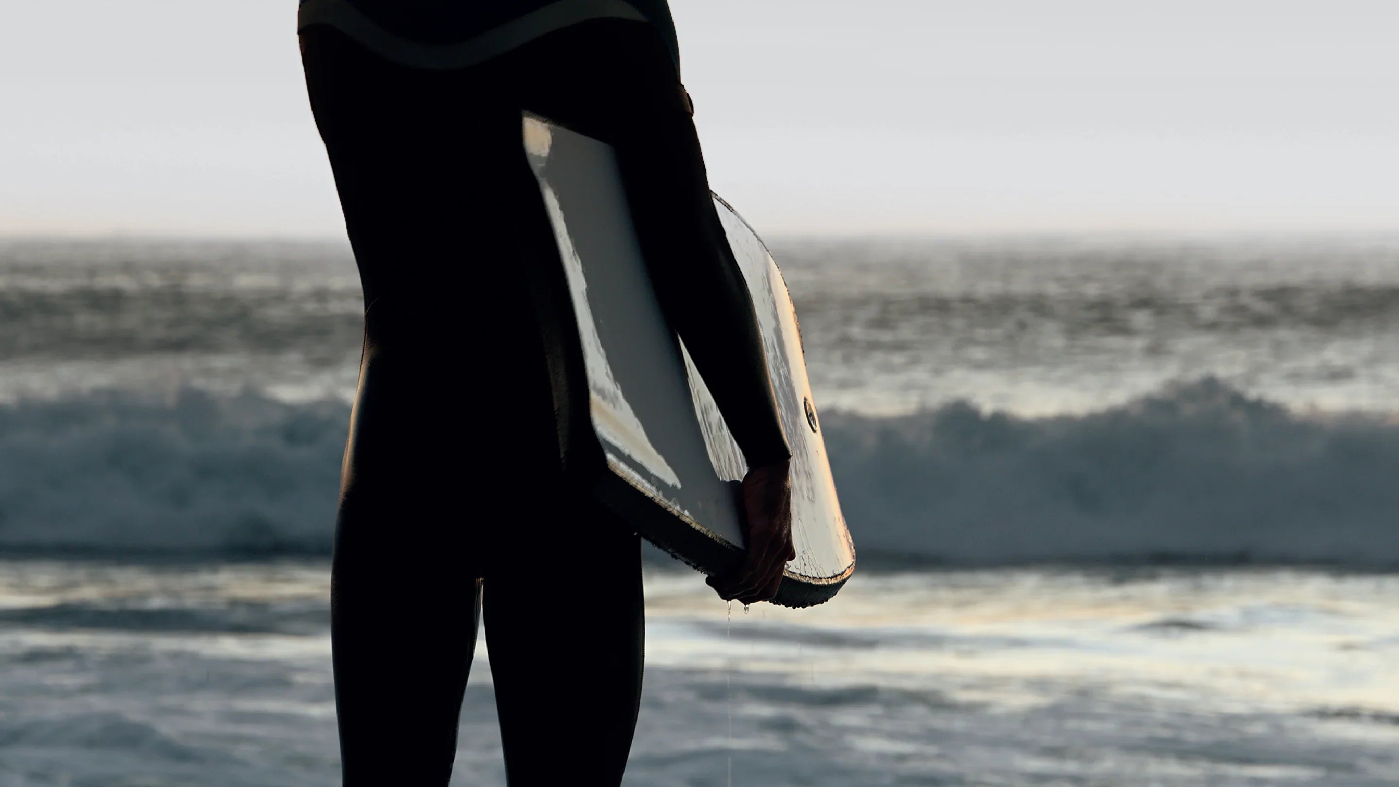 Bodyboarder securing a coiled wrist leash before hitting the waves, available at Noordzee Boardstore. Noordzee Boardstore surfshop Surfschool webshop surfboardrepairs Scheveningen