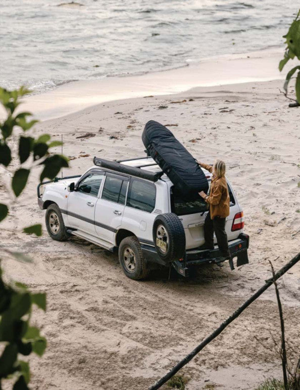 Surfer packing two boards into a durable double boardbag, ready for a surf trip. Noordzee Boardstore surfshop Surfschool webshop surfboardrepairs Scheveningen