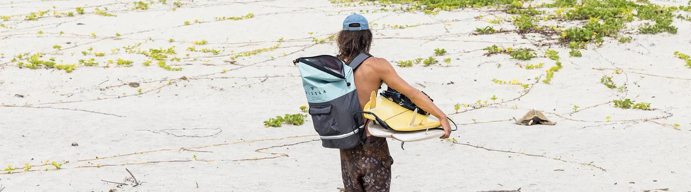 A person packing their towel and clothes into a waterproof dry bag from our travel collection. Noordzee Boardstore surfshop Surfschool webshop surfboardrepairs Scheveningen